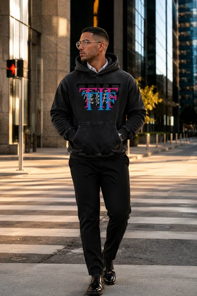 Man walking through the city wearing the black This Is For... hoodie